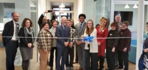 The ribbon is cut during the Willard Hall dedication. The group includes BOV members and student representatives, along with Assistant Dean of Residence Life and Housing Dave Fleming and BOV Rector Heather Mullins Crislip ’95 (far left), UMW President Troy Paino (front) and senior Maggie McCotter (with scissors). Photo by Matthew Brooks.
