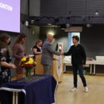 Dean Melissa Jones, Samantha Greer, Madison DeWitt, and Elizabeth Golden look on as Ray Tuttle congratulates Cristopher Anderson at the NSCS induction ceremony.