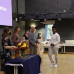 Dean Melissa Jones, Samantha Greer, Madison DeWitt and Elizabeth Golden look on as Ray Tuttle congratulates new NSCS member Yonatan Asfaw.