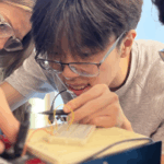 Hannah Steele &rsquo;26, a UMW student mentor and Noyce Scholarship recipient, guides high schoolers Vincent Phan (left) and Alexander Rosas in creating a circuit. Photo by Katie Van Houten &rsquo;27.