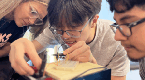 Hannah Steele ’26, a UMW student mentor and Noyce Scholarship recipient, guides high schoolers Vincent Phan (left) and Alexander Rosas in creating a circuit. Photo by Katie Van Houten ’27.